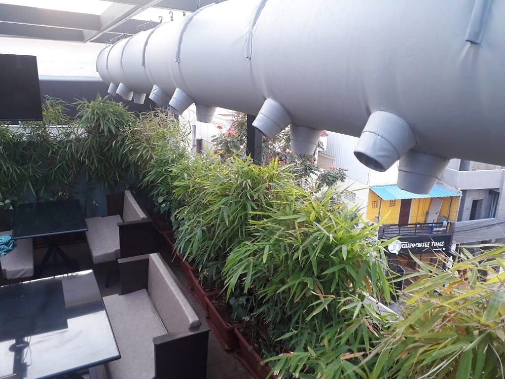 Grey fabric ducts with circular diffusers over a planted conservatory